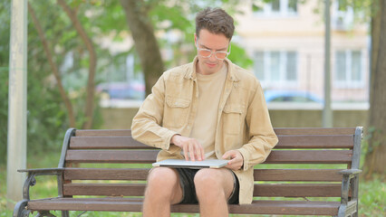 Fototapeta premium Modern Young Man Coming, Sitting and opening Laptop Outdoor
