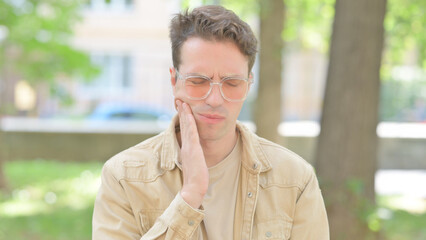Outdoor Portrait of Casual Young Man with Toothache