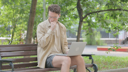 Fototapeta premium Sick Modern Young Man Coughing and Using Laptop Outdoor