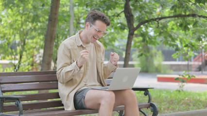 Modern Young Man Celebrating Success on Laptop Outdoor