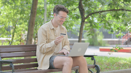 Fototapeta premium Modern Young Man Enjoying Online Shopping on Laptop Outdoor