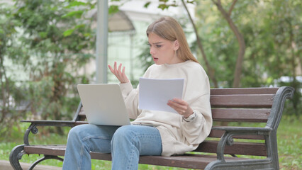 Casual Young Woman Feeling Upset while Reading Contract and Using Laptop Outdoor