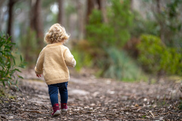 blonde todder walking in a forest on a hike in spring