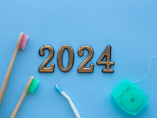 2024 and dental concept. Close up view of photo with 2024, dental floss and two wooden toothbrush...