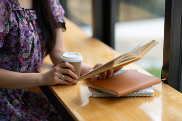 Cute Asian freelance business woman with pleasure reading. Searching for information on mobile phones, tablets, drinking hot drinks on a relaxing weekend away. hobby ideas vacation