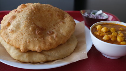 Chole Bhature is a food dish popular in the Northern areas of the Indian subcontinent. It is a combination of chana masala (spicy white chickpeas) and bhaturapuri, a deep-fried bread made from maida.
