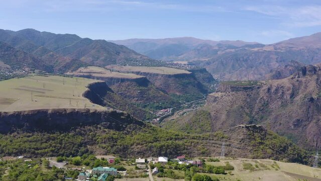 Forward reveal aerial shot of Debed gorge, plateaus and Kayan Fortress on sunny summer day. Lori Province, Armenia.