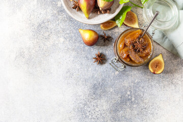 Homemade fig sweet jam in a glass jar with fresh figs on a light gray table. Autumn harvest preservation, healthy fermented food. View from above. Copy space.