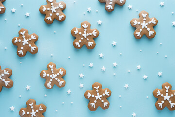 The horizontal wallpaper of many Christmas gingerbread and icing frosted snowflake shapes and gingerbread men isolated on a light blue background in the winter festival. Generative AI.