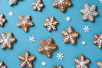 Fototapeta na wymiar The horizontal wallpaper of many Christmas gingerbread and icing frosted snowflake shapes and gingerbread men isolated on a light blue background in the winter festival. Generative AI.
