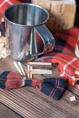 Fototapeta na wymiar Lumberjack set with metal cup, checkered bow, plaid and matches. Copy space
