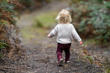 blonde todder walking in a forest on a hike in spring