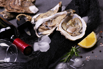 Fresh oysters with a bottle of wine on a black stone background