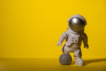 Plastic toy astronaut on colorful yellow background Copy space. Concept of out of earth travel, private spaceman commercial flights. Space missions and Sustainability