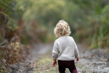 blonde todder walking in a forest on a hike in spring