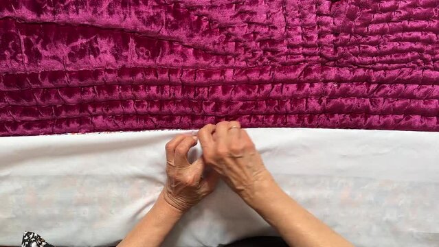 wonderful scene of minimal design blanket for bedroom concept a woman sewing with needle a white bed sheet on a red pink purple satin texture Persian Arabian Turkish style winter bedroom accessories