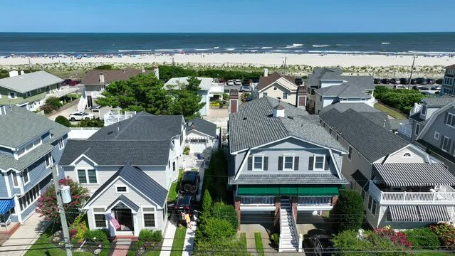 Beach houses in luxury neighborhood. Aerial rising shot revealing Atlantic Ocean and white sand. American flag on rental AirBnB investment property.