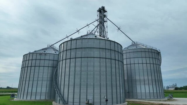 Grain elevators in the breadbasket of America. Low aerial glide with tilt up motion. Establishing shot of large feed and crop storage bins. Brock.