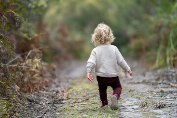 blonde todder walking in a forest on a hike in spring