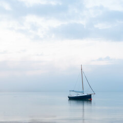 a yacht anchored near the shore at morning blue hour prior to sunrise.