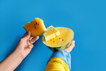 Hand holds a slice of yellow watermelon, as a symbol of Kherson watermelons. The concept of victory and liberation of the Kherson region in Ukraine