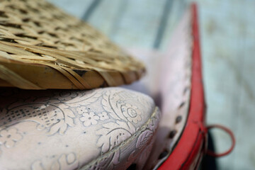 detail of the old design patern cushion from a rickshaw ,with bamboo hat layin on it...