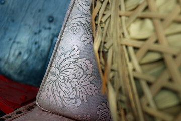 detail of the old design patern cushion from a rickshaw ,with bamboo hat layin on it...