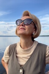 Portrait of happy beautiful elderly senior woman in sunglasses enjoy summer sunny day at beach, sea 