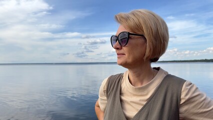 Portrait of happy beautiful elderly senior woman in sunglasses enjoy summer sunny day at beach, sea 