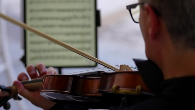 Violinist playing in a concert on a summer terrace. 4k close up video with the detail hand of a violonist singer artist. 
