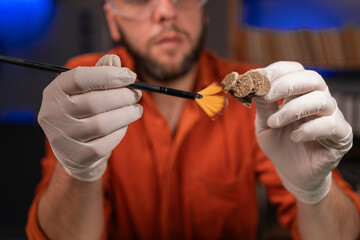 Attractive man restoring ancient coins. Archaeological concept.