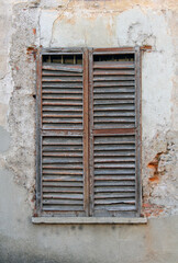 Fototapeta na wymiar old window with shutters, an ancient wall facade with slightly broken wooden window perfect as background textures