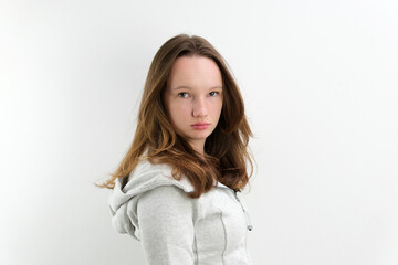 a very strict displeased look of a teenage girl turned her head into the frame looked sternly beautiful hairstyle gray hooded sweatshirt. on a white background