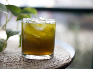 Fresh green tea ice is served in a small glass with a few leaf toppings placed on a placemat, isolated with the surrounding background.