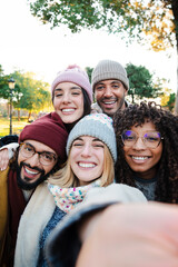 Vertical selfie portrait of a group of multiracial young people having fun in a travel trip on vacations. Front view of cheergul friends looking at camera enjoying together the weekend. High quality
