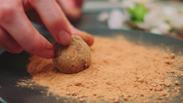 A woman dips a shaped candy in carob powder. Close-up of a table. Cooking in the kitchen