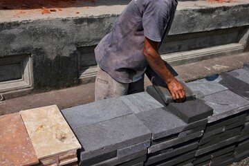 A builder is lifting natural stone