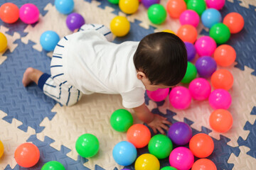 infant baby playing colorful balls in playpen