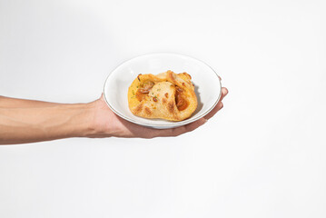 A human hand holding a side dish on a plate