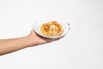 A human hand holding a side dish on a plate