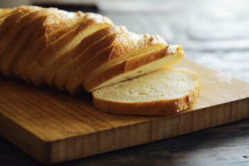 long loaf on a wooden board and knife isolated on a white background. Tasty bread