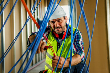 A skilled electrician in construction checking cables for building electric network.