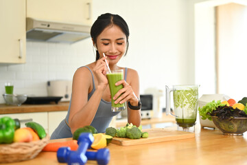 Attractive young woman in sportswear drinking healthy vegetarian smoothie after morning workout....