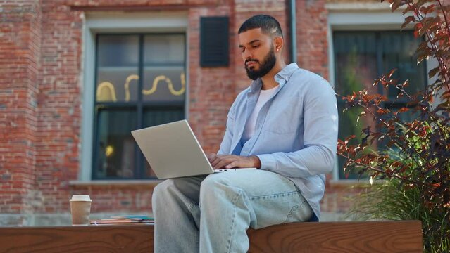 Ambitious male adult holding wireless laptop on knees and being focused on creating personal resume for sending to IT company. Determined man thinking on his positive qualities for employment.