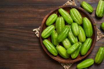 top view flat lay overhead egreen bilimbi kamias fruit in bamboo plate on dark table background. green bilimbi kamias in wood plate on table backgrond. green bilimbi kamias food table backgrond moody