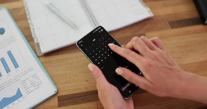 Person using calendar application on mobile device closeup. Female hands scrolling screen on smartphone