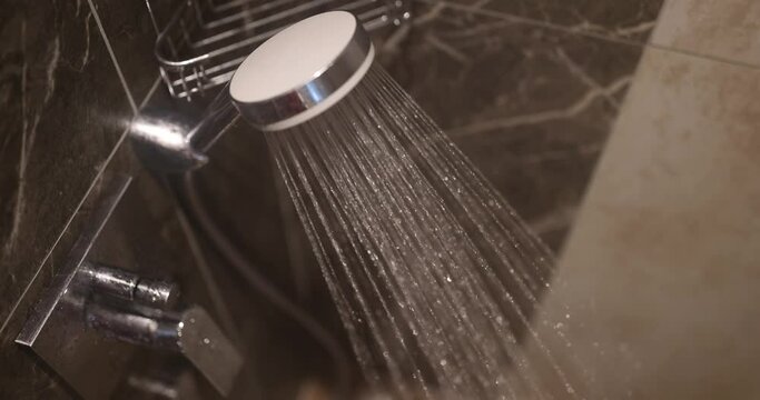 Running water flows from chrome shower faucet. Choosing bathroom shower faucet
