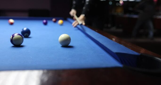 Billiard player hits ball on blue billiard table in club. Player loves to play billiards