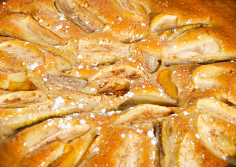 A delicious pie with apples, plums and bananas, sprinkled with cinnamon and powdered sugar.