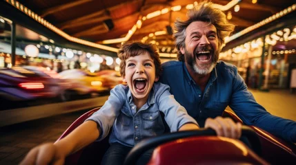 Poster Grandfather and grandson smile and have fun while driving a bumper car in an amusement park. © sirisakboakaew